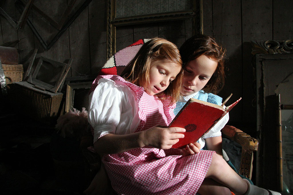 Two girls read a book.