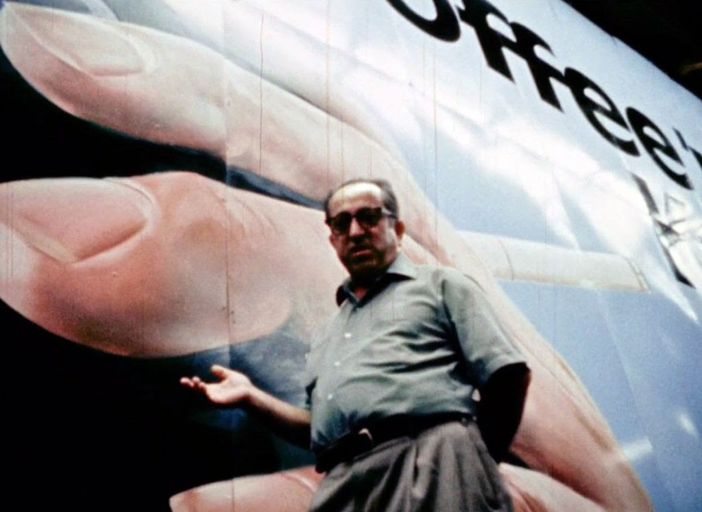 A painters stands next to a sign